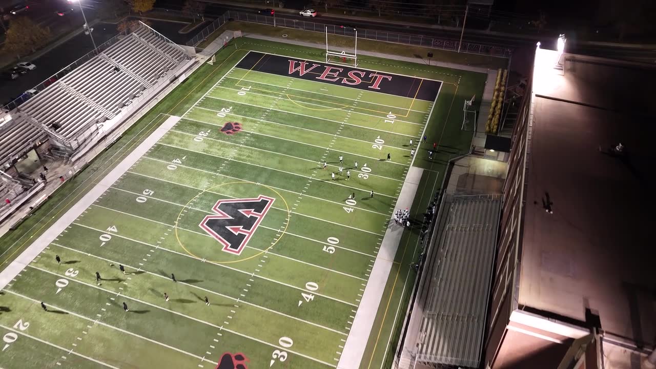 A lit high school football stadium at night, from above